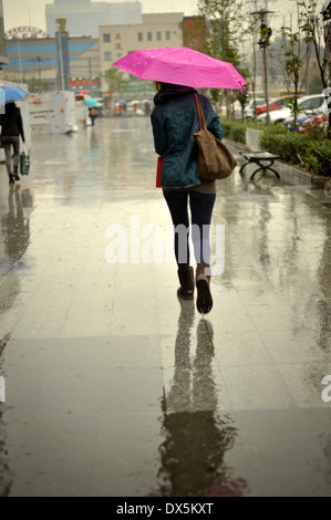 Fille de marcher sous la pluie avec un parapluie rose Banque D'Images