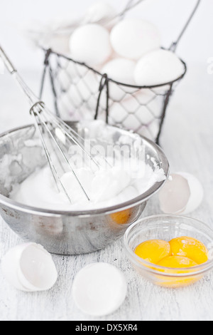 Les blancs d'oeufs battus en acier inoxydable bol, coquilles d'œufs, d'oeufs et d'oeufs dans le panier rustique Banque D'Images