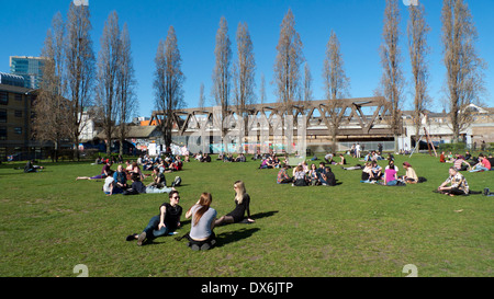 Nouveau pont ferroviaire vue d'Allen Gardens gens assis dans le parc sur une journée de printemps ensoleillée Brick Lane London UK KATHY DEWITT Banque D'Images