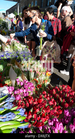 Une femme achetant des tulipes de hyacinthes et diverses fleurs coupées sur un stand de fleurs dans le marché aux fleurs de Columbia Road à la mode Shoreditch Londres E 2 UK KATHY DEWITT Banque D'Images