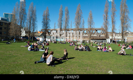 Nouveau pont ferroviaire vue d'Allen Gardens gens assis dans le parc sur une journée de printemps ensoleillée Brick Lane London UK KATHY DEWITT Banque D'Images