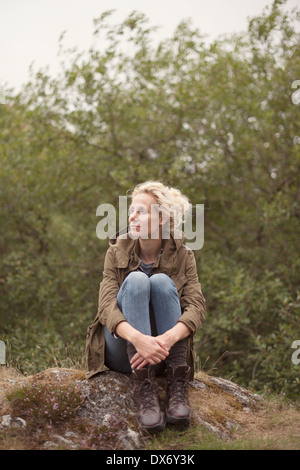 Une jeune femme est assise dans un rock à la campagne Banque D'Images
