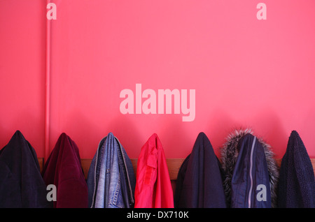 Manteaux et vestes suspendus dans un vestiaire peint rouge. Banque D'Images