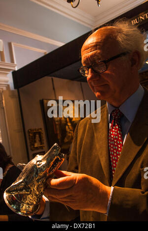 Chelsea Old Town Hall, Londres, 19 mars 2014. Un collecteur examine un étrier tête fox moulé tasse en argent au Chelsea Salon des Antiquaires. Crédit : Paul Davey/Alamy Live News Banque D'Images