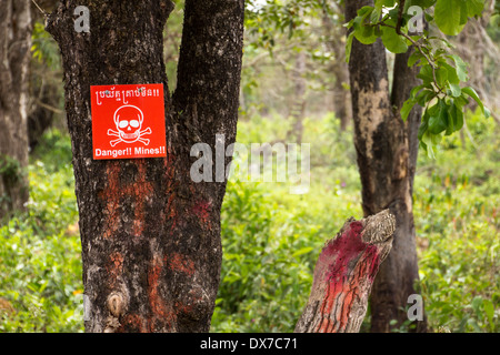 Panneau rouge sur un arbre signalant le danger de mines au Cambodge, la cardamome les montagnes. Banque D'Images