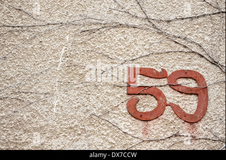 Vieilles et rouillées numéro de rue sur un mur Banque D'Images