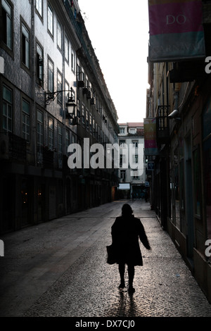 Une femme marchant dans une rue sombre, moody à à Lisbonne, Portugal. Banque D'Images