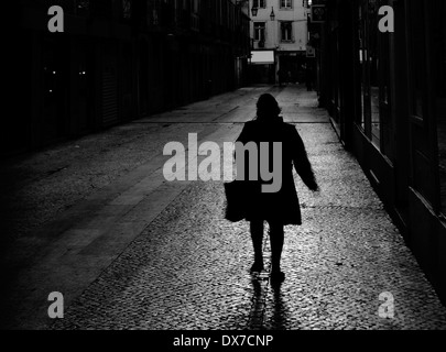 Une femme marchant dans une rue sombre, moody à à Lisbonne, Portugal. Banque D'Images