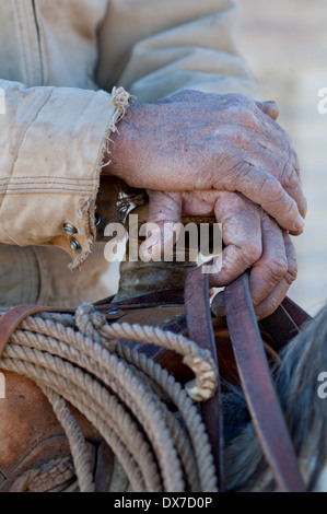 Close up of les mains d'un vieux cowboy sur son cheval tenant sur une selle. Banque D'Images