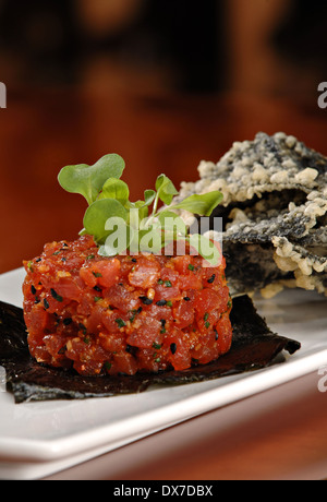 Matières ahi tartare de thon apéritif au sommet d'une feuille de nori et garni de choux vert frais. Servi avec un côté de jetons tempura Banque D'Images