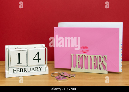 Une carte de Saint Valentin scellées avec un rouge à lèvres rouge baiser dans un letterack, avec un bloc date montrant le 14 février. Banque D'Images