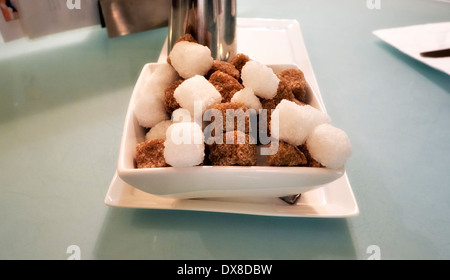 Un plat de cubes de sucre brun et blanc sur une table de café England uk Banque D'Images