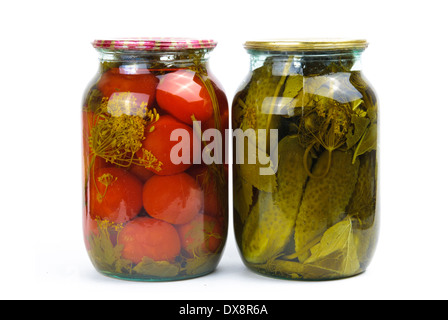 Deux pots en verre transparent coloré de légumes marinés : tomates et concombres Banque D'Images