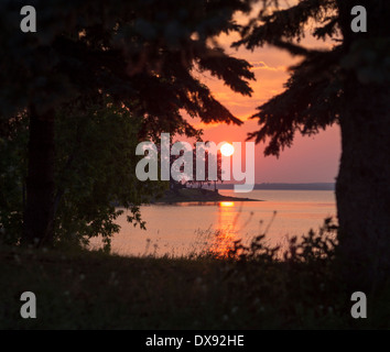 Coucher de soleil sur l'Ottawa. Une boule rouge d'un coucher de soleil sur la rivière des Outaouais, illuminant le ciel avec une lueur orange et rouge. Banque D'Images