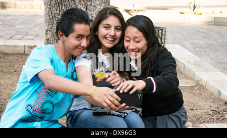 3 bon à la high school kids prendre un cellulaire tout en restant assis sur selfies tree pocket en bordure du quartier centre historique de Oaxaca Banque D'Images