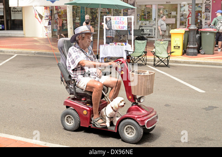 L'homme et le chien équitation un fauteuil roulant motorisé. Banque D'Images