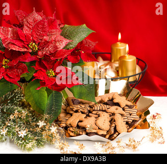 La décoration de l'avent festive avec brûler des bougies, d'or et de fleurs de poinsettia christmas gingerbread cookies Banque D'Images