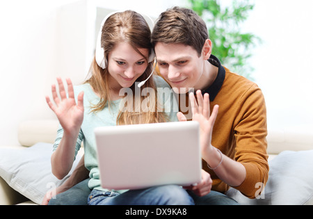 Jeune couple sympathique est en train de parler à ses amis ou en famille grâce à l'ordinateur avec la vidéo de chat Banque D'Images