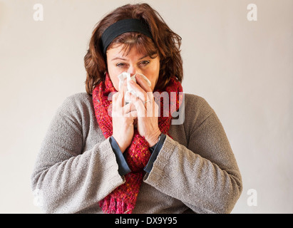 Femme avec écharpe rouge et handkerchieif blowing nose Banque D'Images