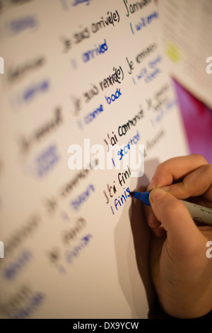 Une adolescente verbes d'apprentissage écrit son GCSE French language school devoirs à la maison, au Pays de Galles UK Banque D'Images