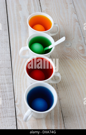 Portrait de quatre tasses avec du colorant pour les oeufs de Pâques. Les tasses sont remplies avec du jaune, bleu, rouge et vert colorant. Banque D'Images