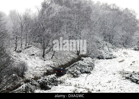 La couverture de neige piste en forêt près de Sherrifmuir, Stirling, Ecosse. 4x4 Voir la conduite sur route. Banque D'Images