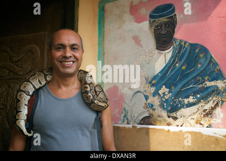 Tourist posant avec un serpent autour de son cou, au Bénin, en Afrique de l'Ouest Banque D'Images