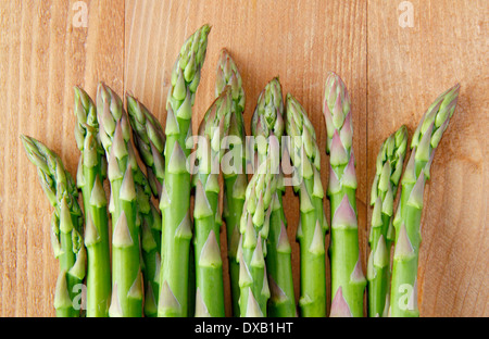 Les pointes d'asperges vertes fraîches/branches contre fond de bois, UK Banque D'Images