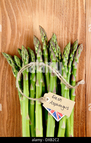 Un tas de frais vert asperges avec contre étiquette, rustique en bois vintage background, UK - avec copie espace. Banque D'Images