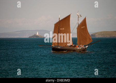 Les voiliers d'lugger (un bateau de pêche traditionnel), le 'Ripple' dans la baie de St Ives, avec phare de Godrevy, Cornwall, UK. Banque D'Images