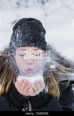 Belle Jeune femme tenant de la neige dans ses mains et en soufflant avec une vitesse d'obturation lente Banque D'Images