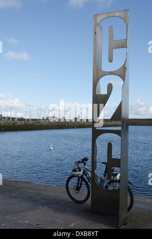 Un vélo de montagne en appui sur le C2C sculpture à Whitehaven Harbour sur une journée ensoleillée Banque D'Images