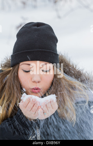 Belle Jeune femme tenant de la neige dans ses mains et en soufflant avec une vitesse d'obturation lente Banque D'Images