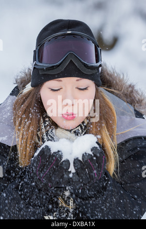 Belle Jeune femme tenant de la neige dans ses mains et en soufflant avec une vitesse d'obturation lente Banque D'Images