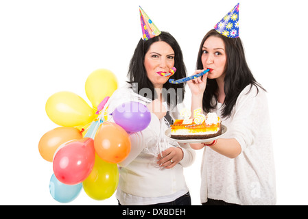 Joyeux anniversaire de femme plus jeune célébrer avec son amie et souffler de l'ensemble des parties de l'avertisseur sonore Banque D'Images