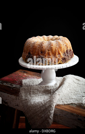 En gâteau bundt sur table en bois, fond noir Banque D'Images