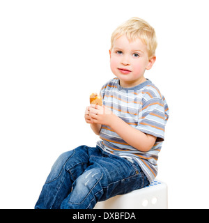 Cute little boy eating cookie délicieux isolé sur fond blanc Banque D'Images