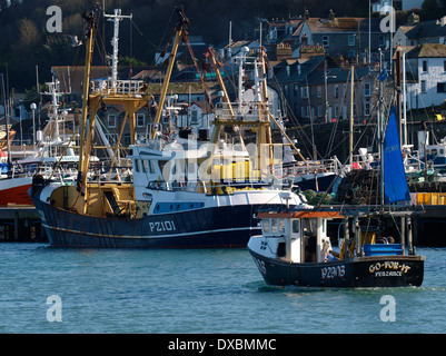 Petit chalutier de pêche en passant un plus grand, le port de Newlyn, Penzance, Cornwall, UK Banque D'Images