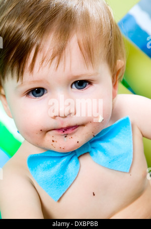 Enfant avec blue Bow-tie est de célébrer son premier anniversaire, et mange des gâteaux Banque D'Images