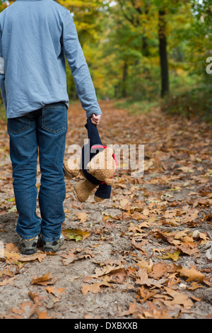 Boy holding a teddy bear Standing alone in a forest Banque D'Images