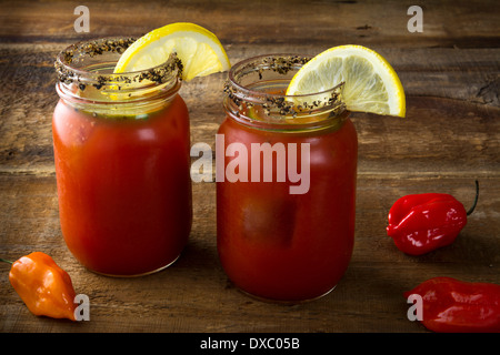 Deux pot Mason Bloody Mary ou Caesars avec citron et chaux sur fond de bois Banque D'Images