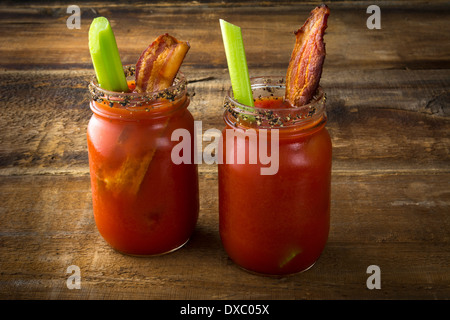 Deux pot Mason Bloody Mary ou Caesars avec bacon sur fond de bois Banque D'Images