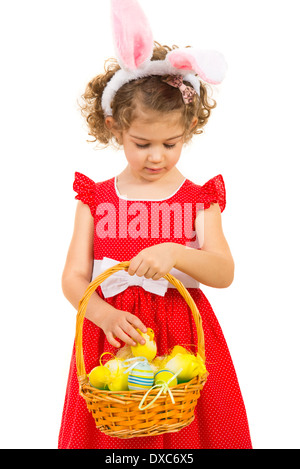 Belle fille avec des oreilles de lapin contrôler les oeufs de Pâques dans un panier isolé sur fond blanc Banque D'Images