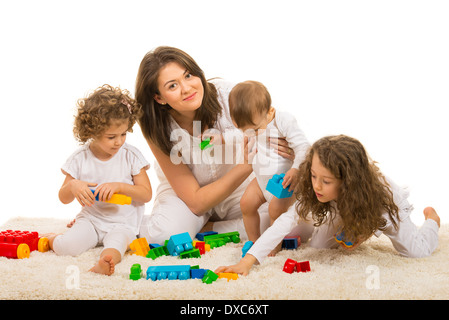 Beauté maman jouant avec ses enfants à la maison et s'asseoir ensemble sur des tapis de fourrure Banque D'Images