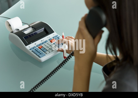 Femme professionnelle sur téléphone using calculator Banque D'Images