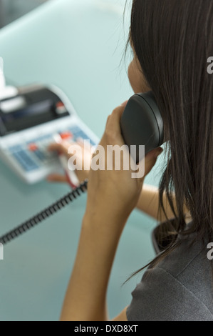 Femme professionnelle sur téléphone using calculator Banque D'Images