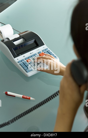 Femme professionnelle sur téléphone using calculator Banque D'Images