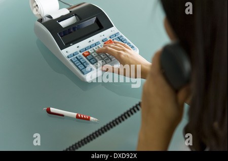 Femme professionnelle sur téléphone using calculator Banque D'Images
