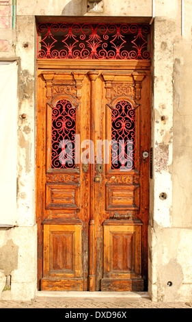 Ancienne porte d'entrée faite de bois sculpté et peint en rouge décorations métalliques. Banque D'Images
