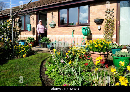Ravenshead, Dorset, UK. Dame âgée dans le début du printemps soleil tending to the garden.Certaines parties de l'Angleterre connaissent un début de l'explosion de couleurs du printemps, l'an dernier à cette époque il y avait encore de la neige dans de nombreuses régions. Banque D'Images